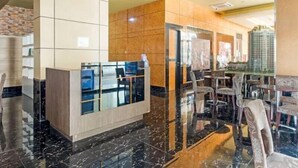 A modern hotel lobby with a reception desk, seating area, and a glass partition. - OYO 3691 Apartment Saladin Mansion (Depok)