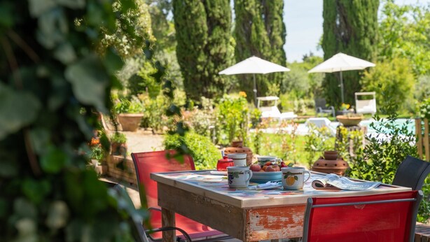 An outdoor dining area with a table set for two, surrounded by greenery and tall trees. - Villa in Gambassi Terme with 4 bedrooms sleeps 9 (Gambassi Terme)