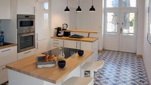 Une cuisine moderne avec des armoires blanches, un plan de travail en bois et un luminaire suspendu noir.