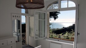 Une chambre dotée d’une grande fenêtre donnant sur la mer et les collines.