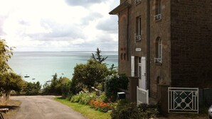 Un bâtiment avec vue sur la mer, un chemin pavé et quelques espaces verts.