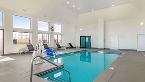Una piscina interior con agua cristalina, un trampolín y varias sillas de descanso.