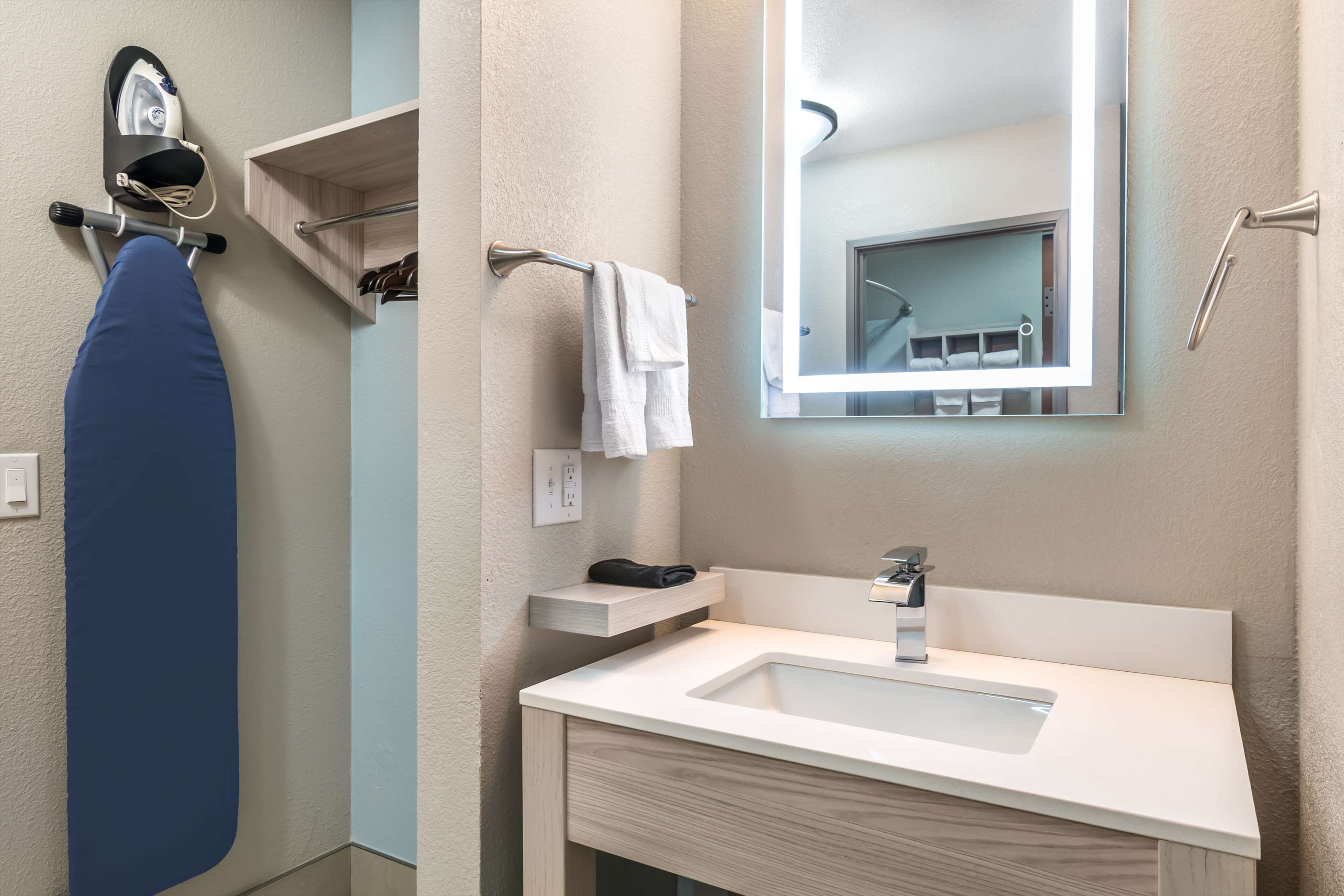 Un baño moderno con lavamanos blanco, espejo y toallero.