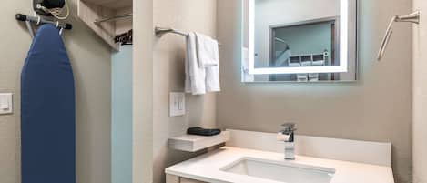 A modern bathroom with a white sink, a mirror, and a towel rack.