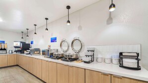 Un área de cocina moderna con electrodomésticos de acero inoxidable, una cafetera y una barra desayunadora.