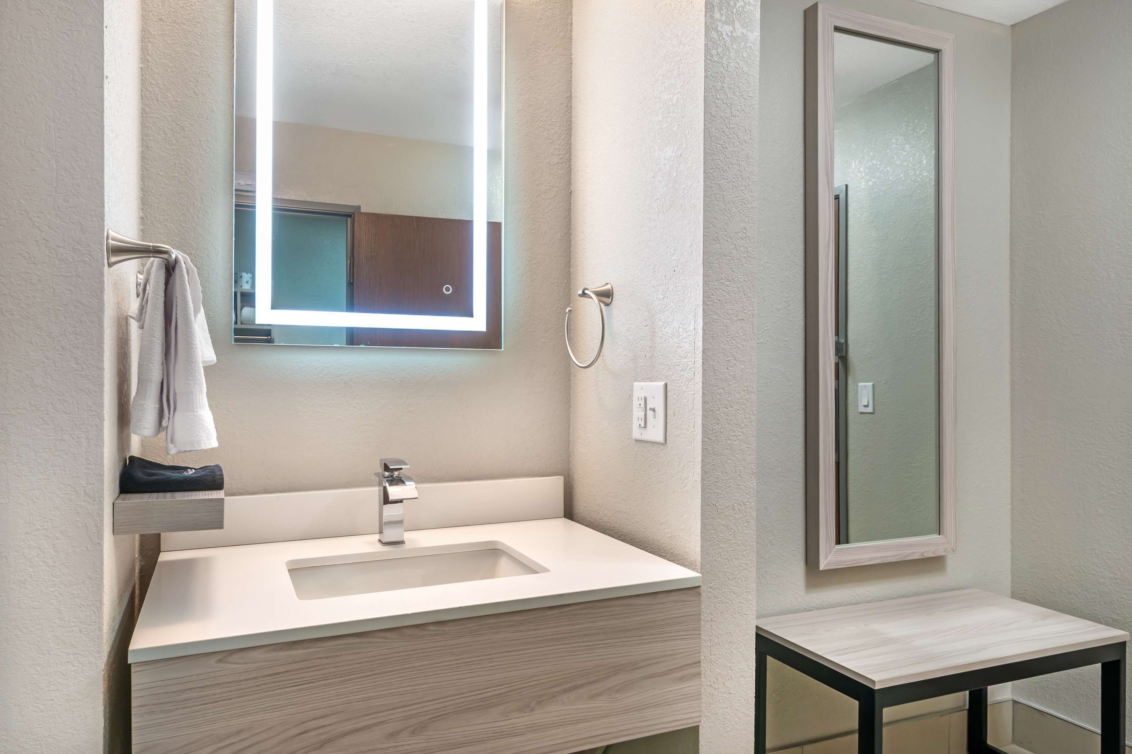 A modern bathroom with a large mirror, a sink, and a shower.
