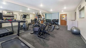 Un gimnasio con cintas de correr, elípticas y una banca para pesas.