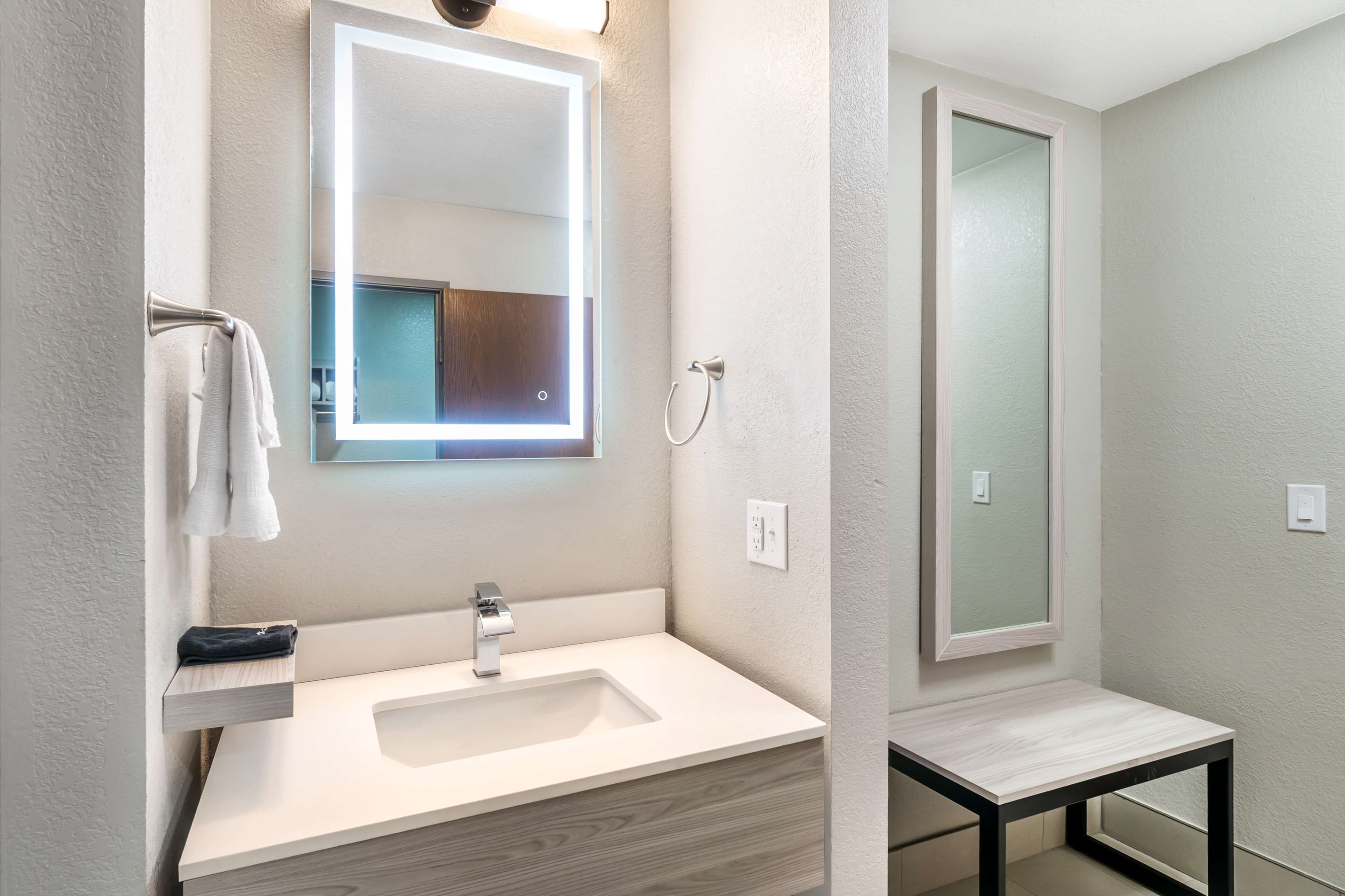 Un baño moderno con un lavabo blanco, un espejo y una zona de ducha.