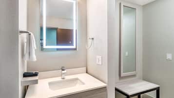 Un baño moderno con un lavabo blanco, un espejo y una zona de ducha.