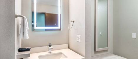 Une salle de bain moderne avec un lavabo blanc, un miroir et un espace douche.