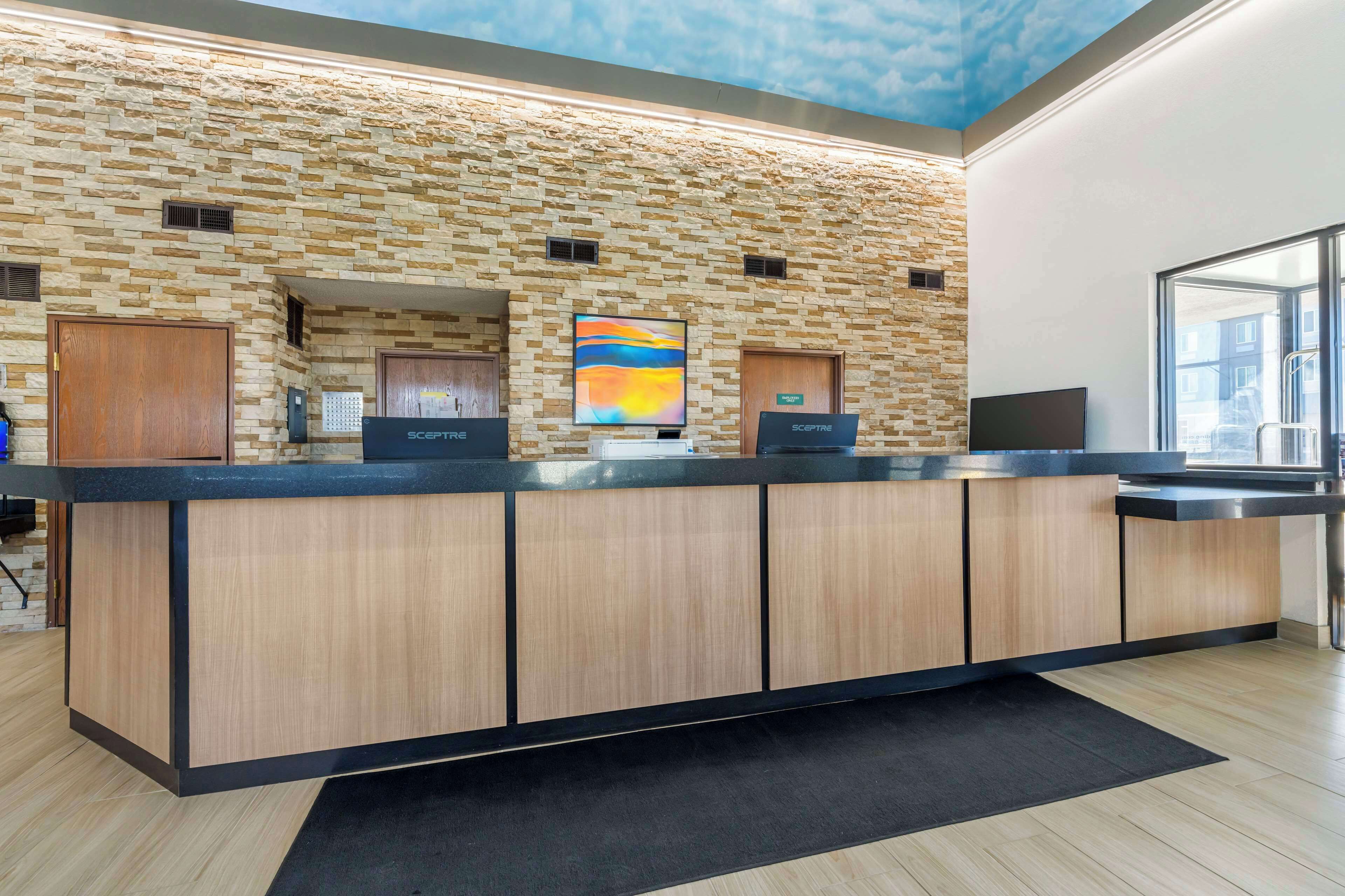 A reception desk with a stone wall backdrop, a large window, and a flat-screen TV.