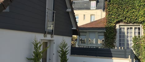 Une cour avec un sol recouvert de gravier, un banc et deux plantes en pot.