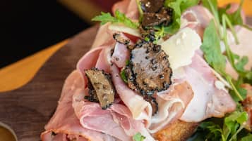 A sandwich with various toppings on a piece of bread, placed on a wooden surface.