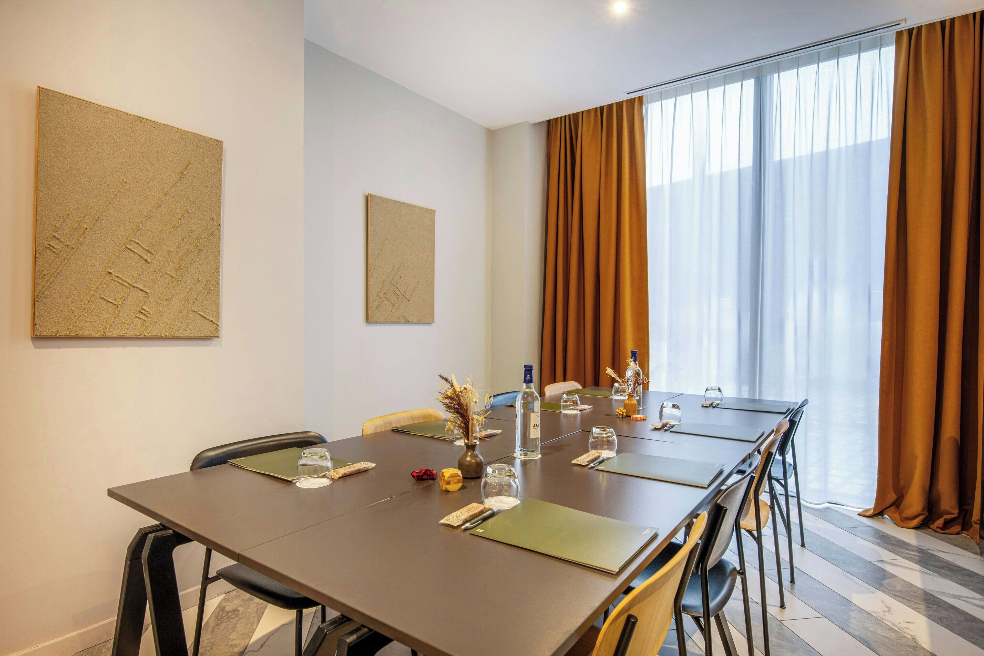 A conference room with a long table, chairs, and a large window with curtains.