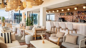A modern lounge area with wicker hanging lights, comfortable seating, a bar with a variety of bottles, and a view of the city. - Renaissance Bordeaux Hotel (Bordeaux)