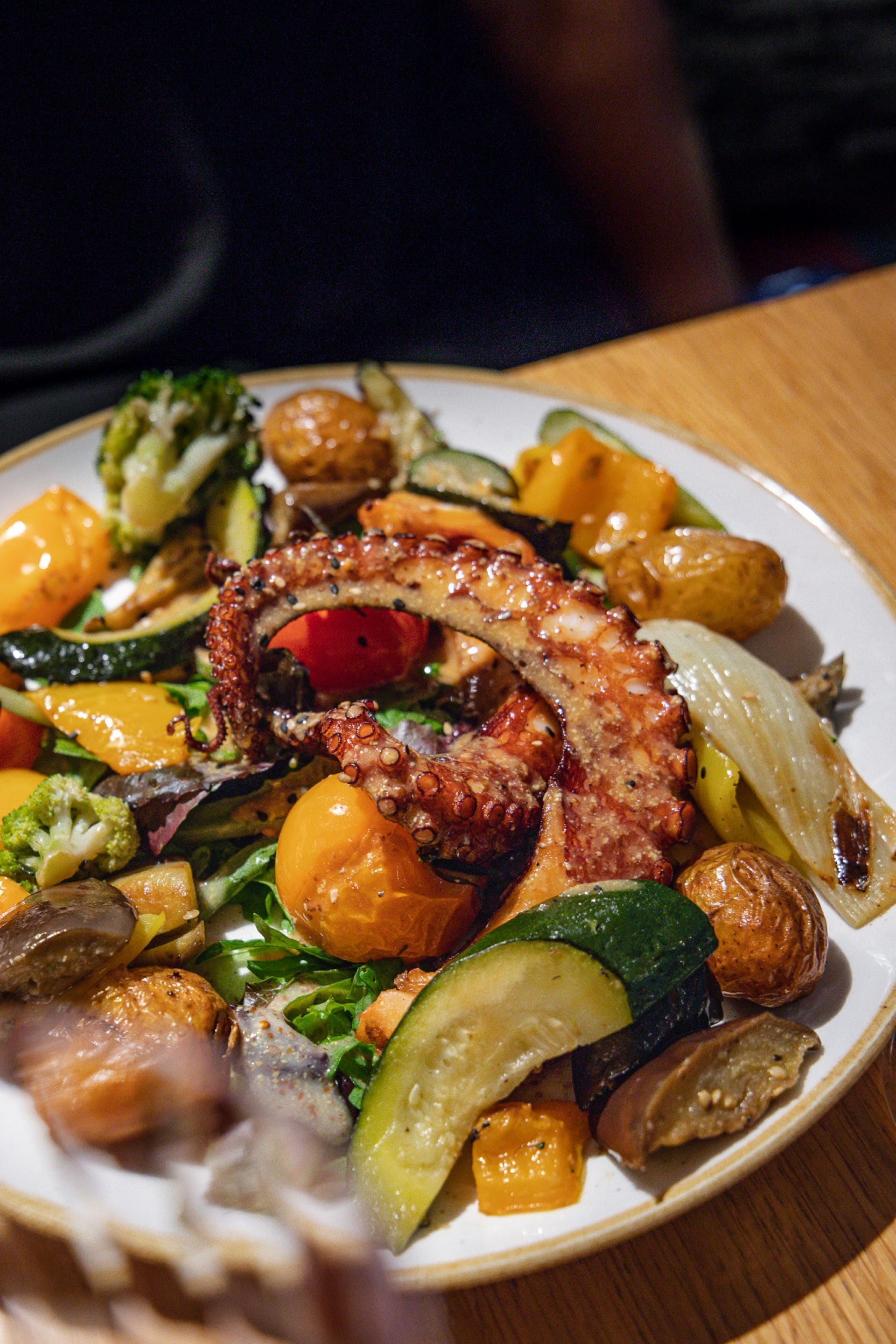 Un plato de comida con pulpo, verduras y patatas.