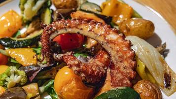 Un plato de comida con pulpo, verduras y patatas.