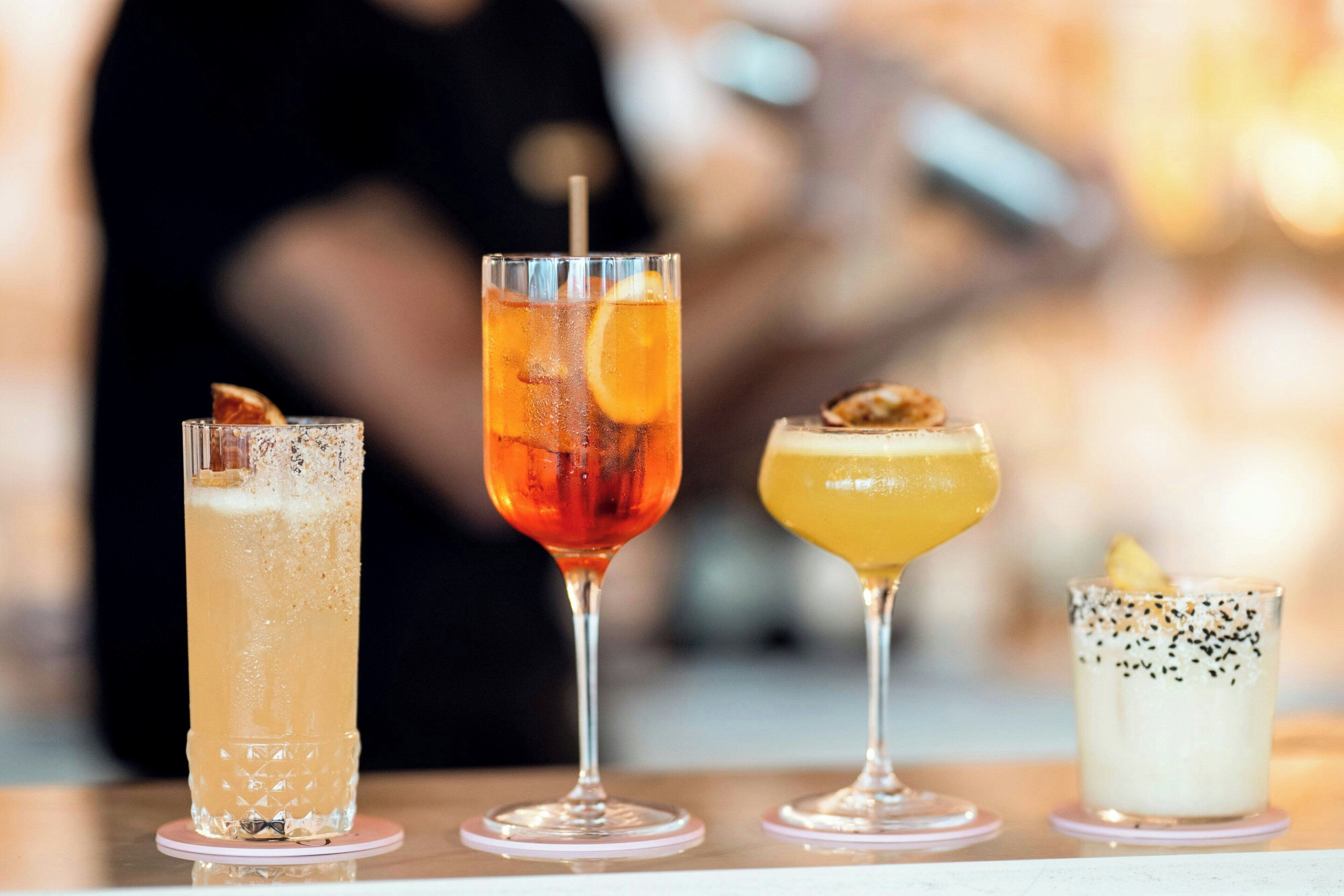 Vier verschiedene Cocktails auf einem Tisch.