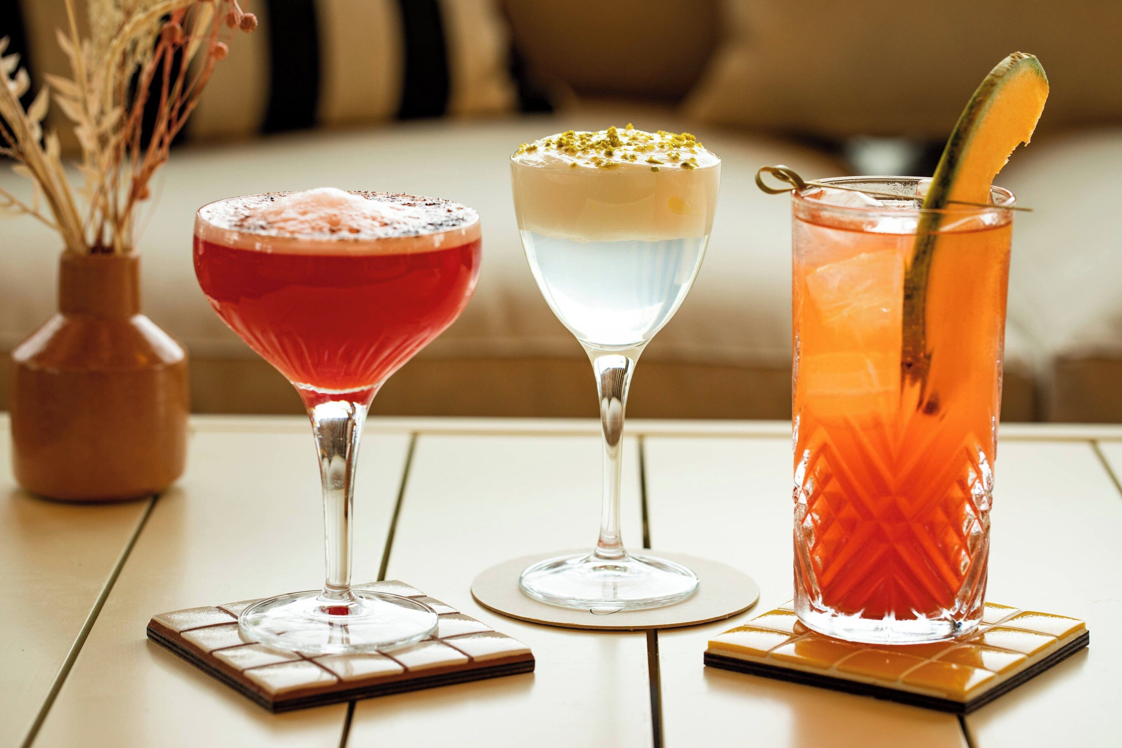 Three drinks on a table with coasters.