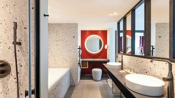 Un baño moderno con una bañera independiente, un espejo grande con luz circular y un tocador doble.