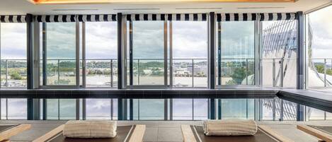 A modern spa area with large windows, wooden loungers, and a view of the city.