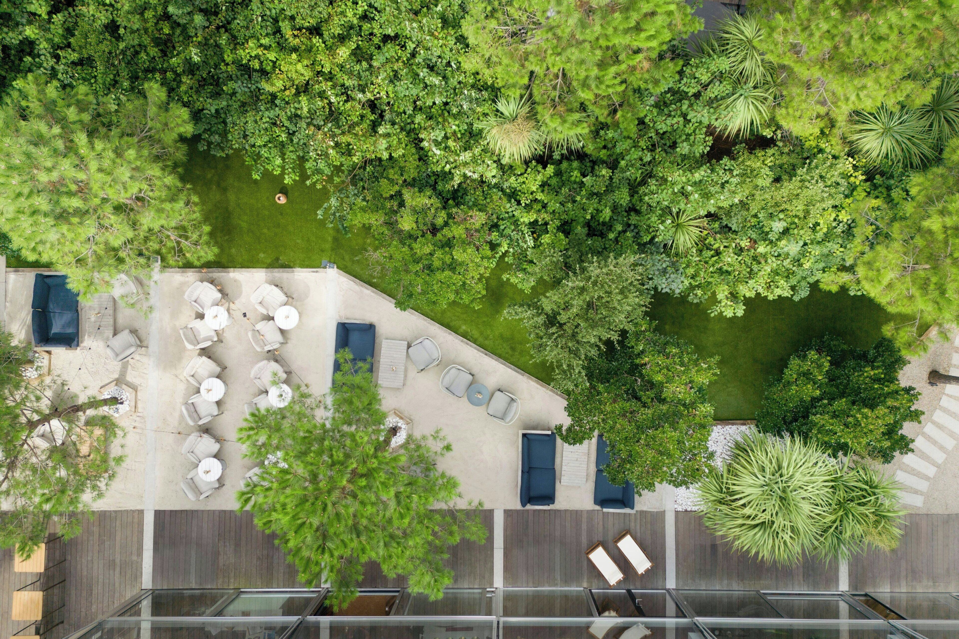 An aerial view of a rooftop garden with outdoor seating and a glass balustrade.