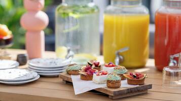 Una mesa con diferentes alimentos y bebidas, entre ellos, tartas de frutas y varios tipos de jugos.