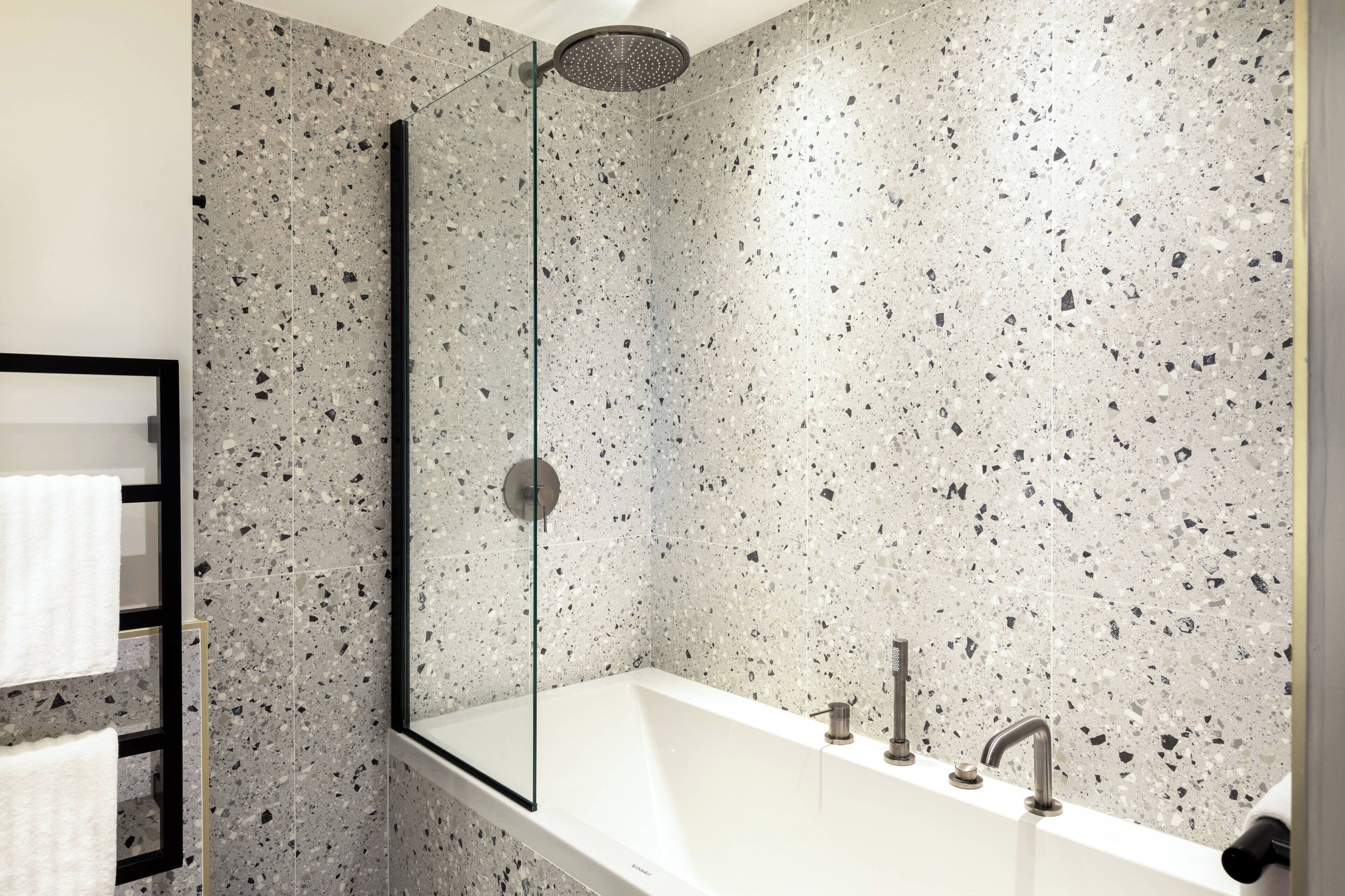A modern bathroom with a freestanding bathtub, a glass shower enclosure, and a built-in towel rack.