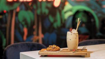 Un postre con una galleta y un vaso de bebida helada sobre una tabla de madera.