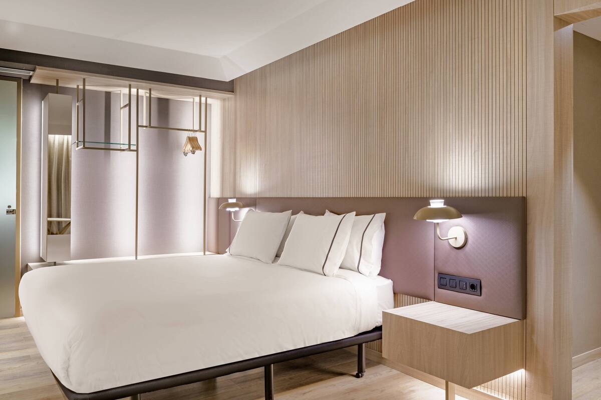 Une chambre d’hôtel moderne avec un grand lit, des tables de chevet et une armoire intégrée.