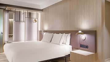 A modern hotel room with a large bed, bedside tables, and a built-in wardrobe.