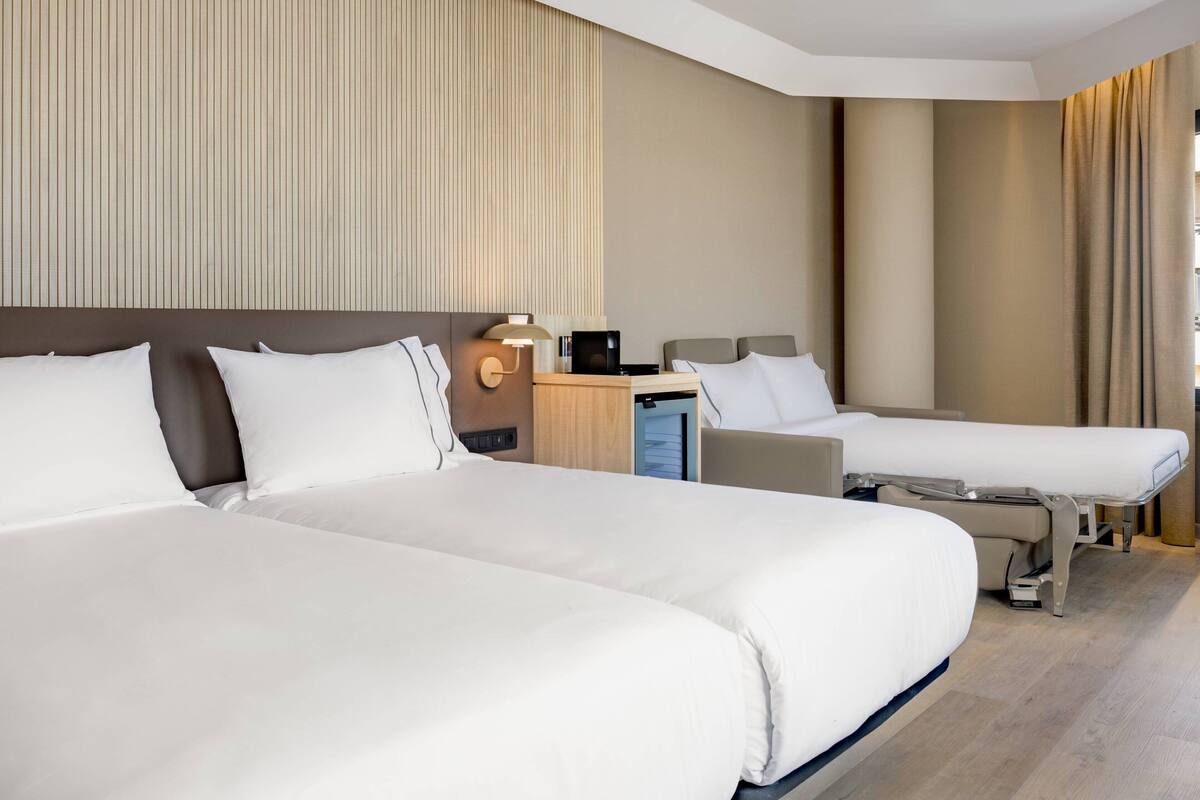 Ein Hotelzimmer mit zwei Betten, einem Schreibtisch und einer Lampe.