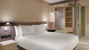 Habitación de hotel moderna con una cama grande, lámparas de noche, una mesita de noche y un armario empotrado con espejo.