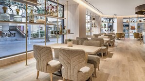 Een moderne eetruimte met een lange tafel en comfortabele stoelen, omringd door planken met decoratieve objecten.