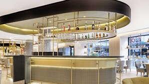 Een moderne bar met een gebogen toonbank, diverse flessenrekken en een scala aan glazen.
