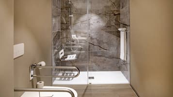 Un baño moderno con cabina de ducha de vidrio, paredes de mármol y lavabo blanco.