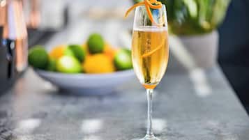 A glass of champagne with an orange peel garnish on a bar counter.