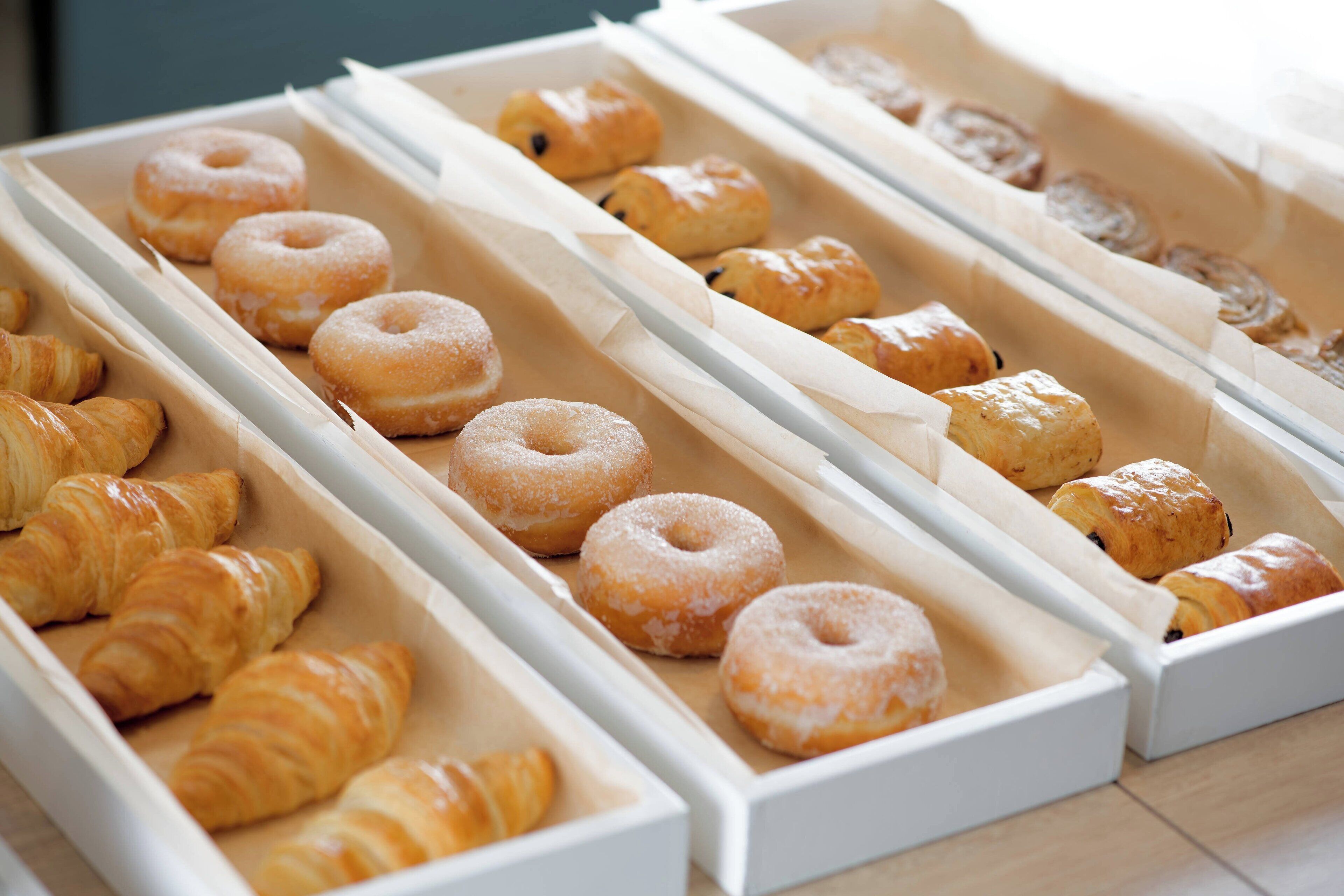 A bakery display with various pastries including croissants and donuts.