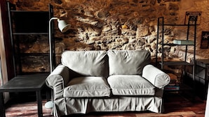 Una sala de estar moderna con una pared de piedra, un sofá gris, una lámpara de pie y una pequeña mesa.