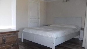 Un dormitorio con un aparador de madera, una cama blanca y una puerta blanca.