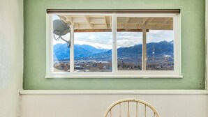 Ein Zimmer mit Fensterblick auf eine gebirgige Landschaft.