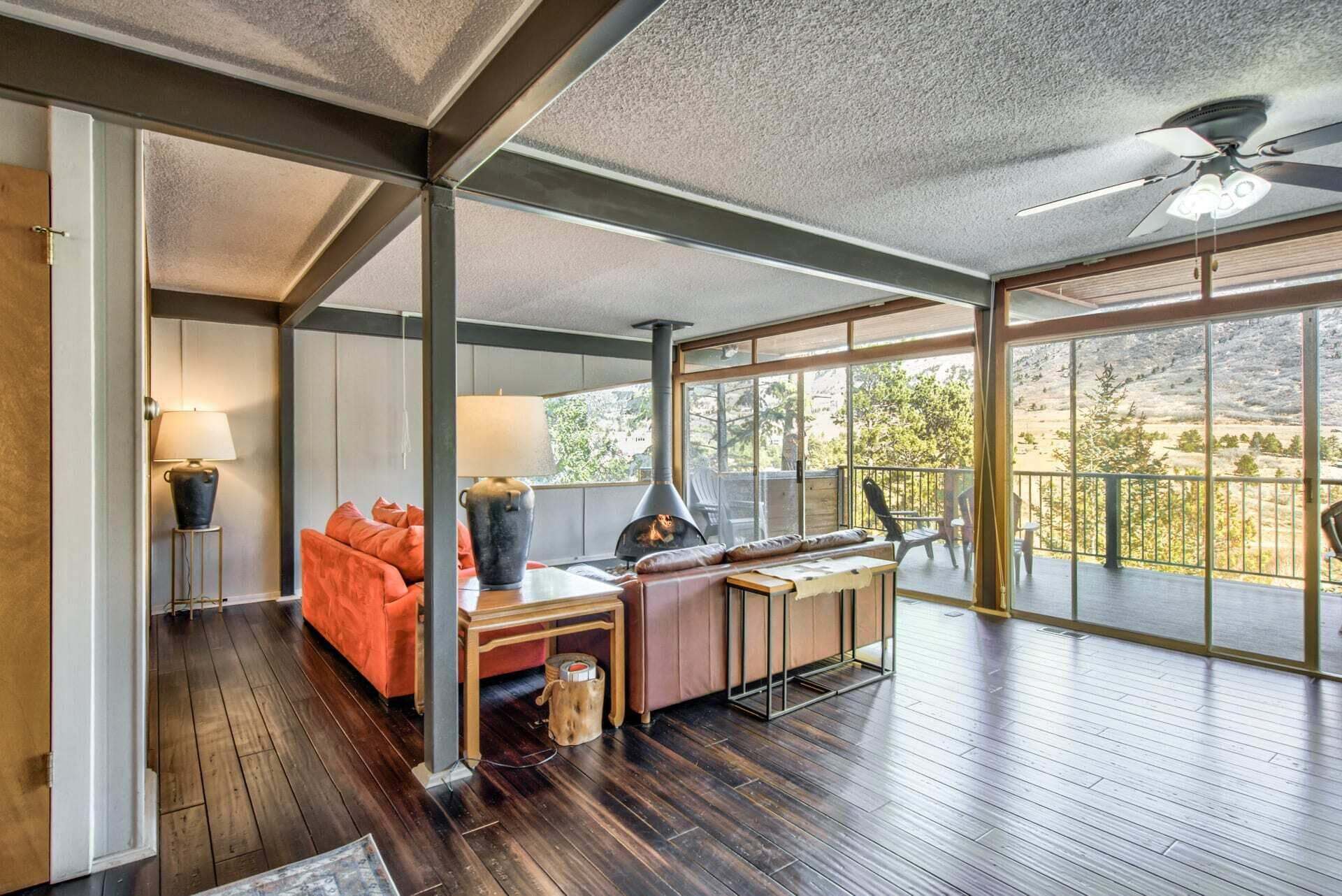 A spacious room with a large window, a ceiling fan, and a fireplace.