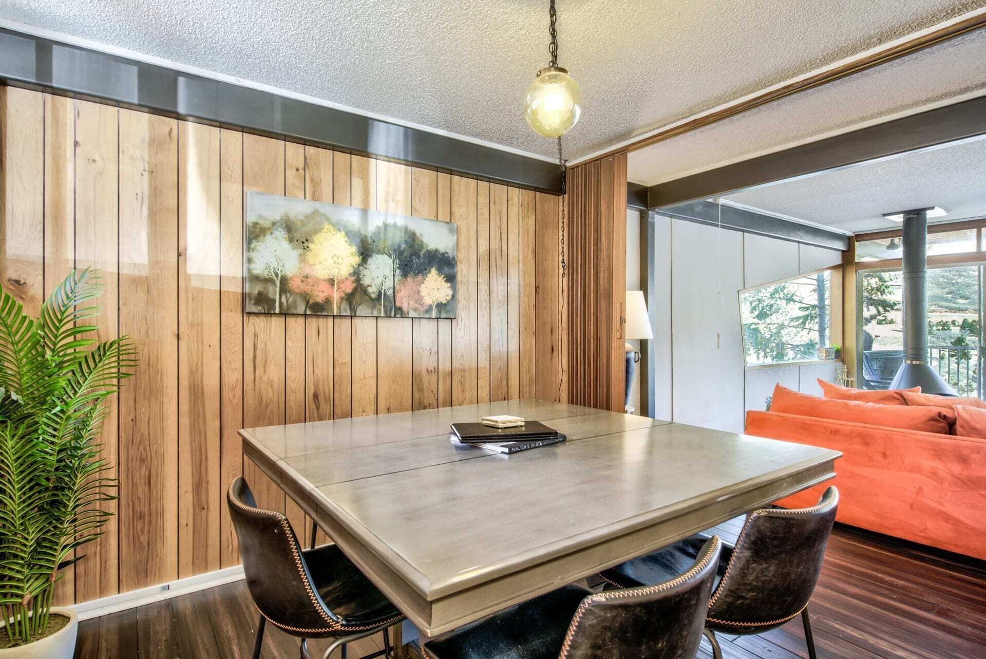 A dining area with a wooden wall, a table, and chairs.