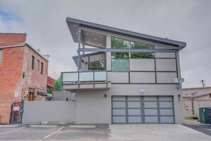 Ein modernes, zweistöckiges Gebäude mit Garage, großen Fenstern und einem Balkon.