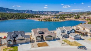 Un quartier résidentiel avec des maisons situées près d’un lac, entouré de montagnes.