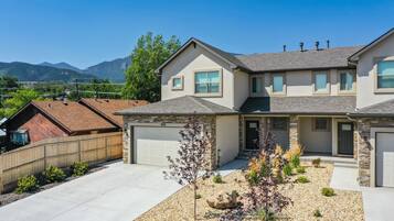 A two-story house with a stone facade, a garage, and a landscaped front yard with a small tree and decorative rocks.