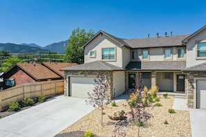 A two-story house with a stone facade, a garage, and a landscaped front yard with a small tree and decorative rocks.