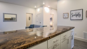 A modern kitchen with a large island, white cabinetry, and a 'Live Simply' sign. - 2bdmodern Garden Level-perfectoff Downtown Area (Colorado Springs)