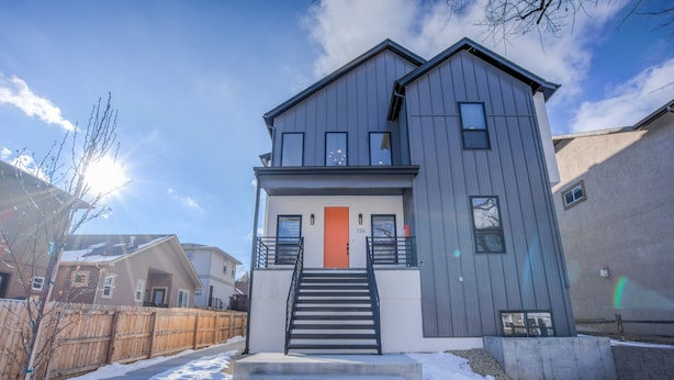 A two-story house with a grey exterior, a red door, and a staircase leading to the entrance. - 2bdmodern Garden Level-perfectoff Downtown Area (Colorado Springs)