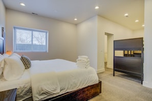 A bedroom with a bed, a window, a bedside lamp, a stack of towels, and a wardrobe. - 2bdmodern Garden Level-perfectoff Downtown Area (Colorado Springs)